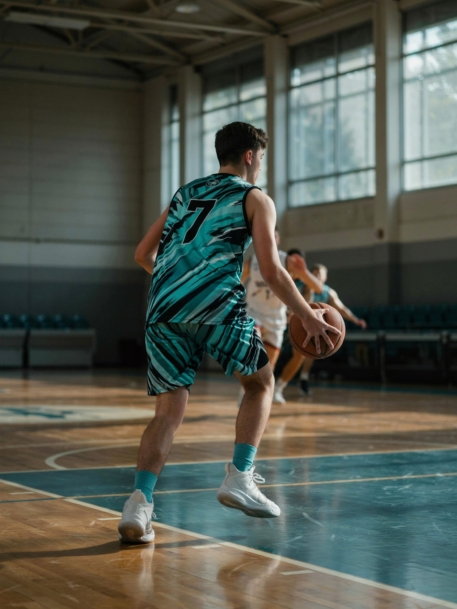 A basketball player dribbling up the court in a custom teal and black jersey with number 7